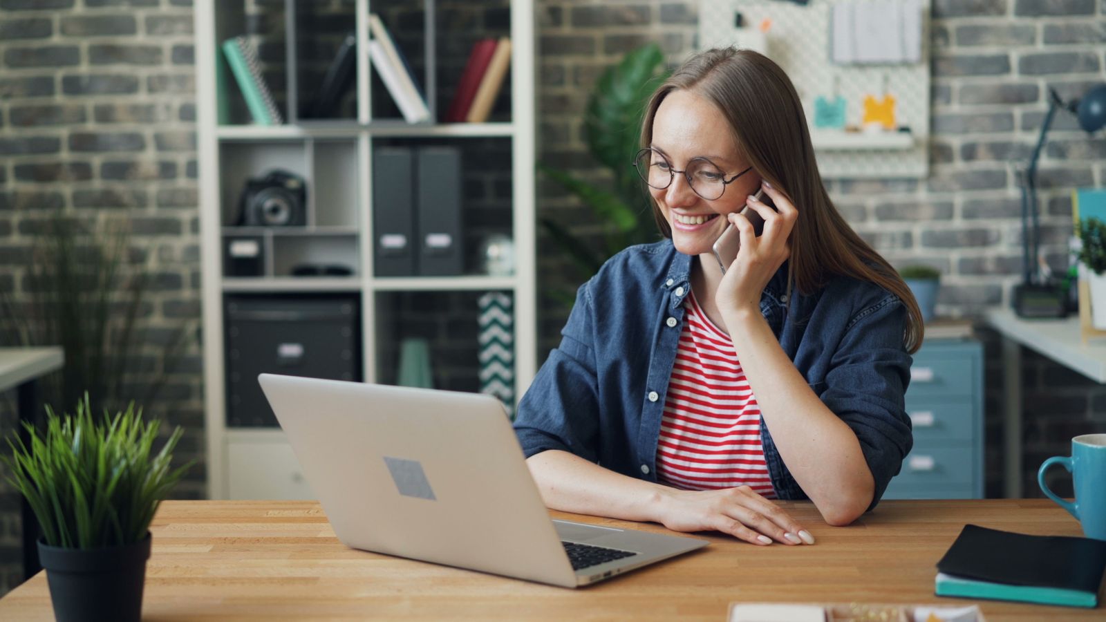 Profissional sorrindo ao telefone na frente do notebook